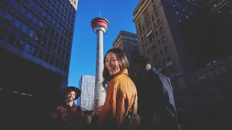 couple listening to a street busker play guitar in front the the Calgary Tower