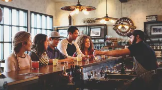 group of four at the bar of Eau Claire Distillery sampling farm to table spirits