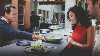 server setting down a dish in front of two patrons at the bar top at Fortunas Row