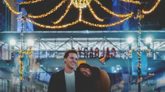couple walking along Stephen Ave with outdoor lights strung behind them