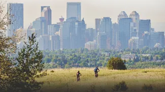 two people biking in Nose Hill park with the downtown skyline in the background