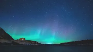 The Northern Lights shine brightly above Prince of Wales Hotel in Waterton Lakes National Park at night