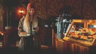 woman carrying a sandwich and latte in a local calgary coffee shop