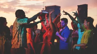 group of friends dancing on an outdoor rooftop with the Calgary skyline in the background