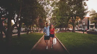 Couple walking a tree-lined street on 17th Ave with shopping bags