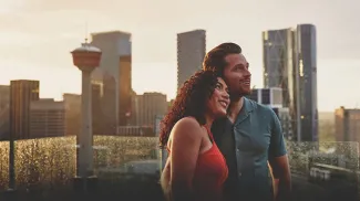 a man and a woman standing on a balcony with a city skyline
