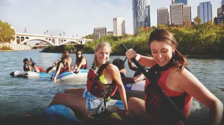 Group of young women rafting down the Bow River in Calgary with the city skyline in the background