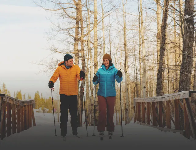 A couple cross-country skiing over a bridge in Calgary