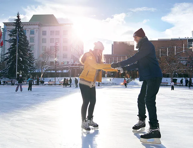 couple learning to skate together during winter in Calgary's Olympic Plaza downtown