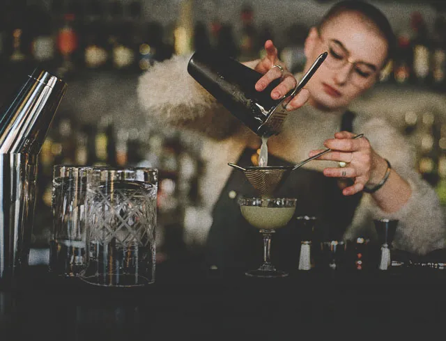 Bartender at Proof pouring a cocktail