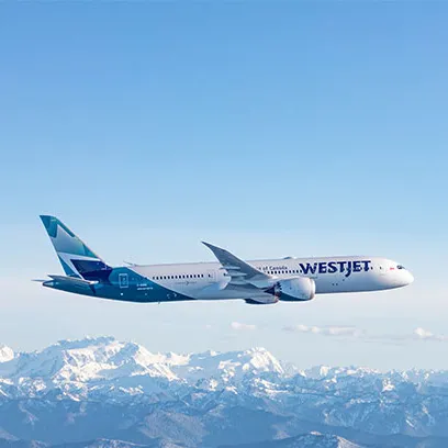 WestJet Aircraft flying over mountain range