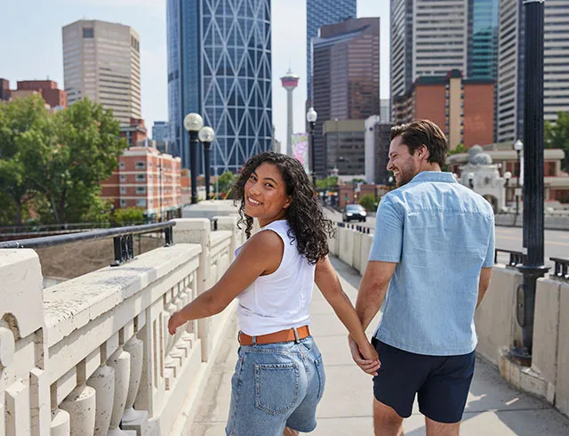 Couple holding hands while walking across Centre Street Bridge in Calgary