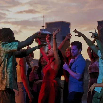 group of friends dancing on an outdoor rooftop with the Calgary skyline in the background