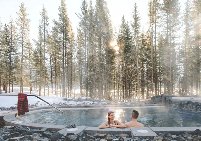 Couple soaking in the hot pool at the Kananaskis Nordic Spa (Photo credit: Travel Alberta/Mike Seehagel).