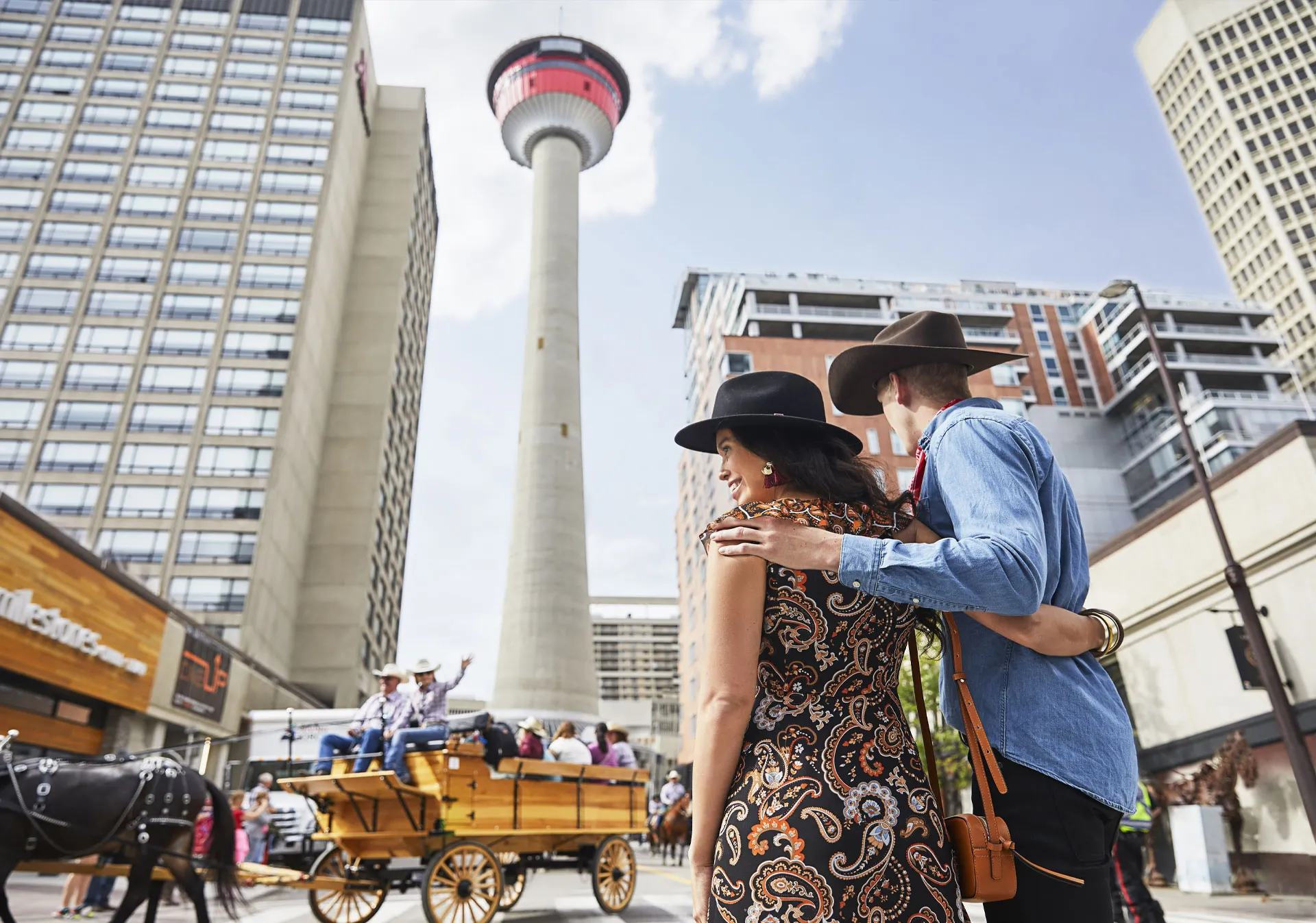 Man and women watching the Calgary Stampede parade pass below the Calgary tower