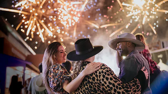 Group of three friends watching the fireworks on the grounds of the Calgary Stampede