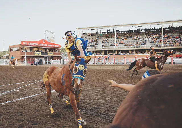 Team mates passing baton on horse during Stampede Relay Race