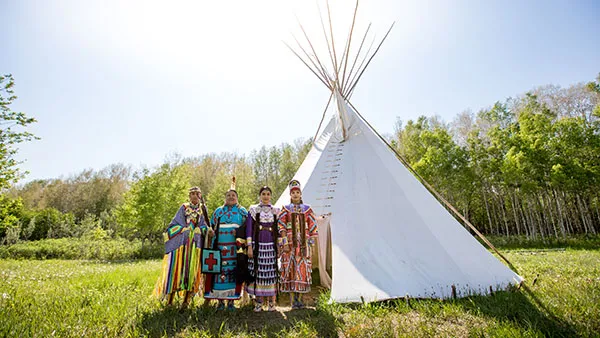 Members of the Siksika Blackfoot Nation stand in front of a tipi