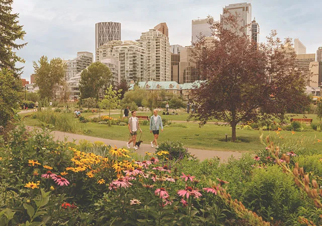 LGBTQ couple walking their dog along a pathway in Prince's Island Park during summer with flowers in the foreground