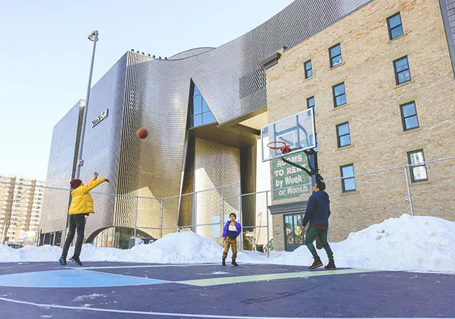 family of 3 playing basketball at Calgary's East Village Bounce Park during winter