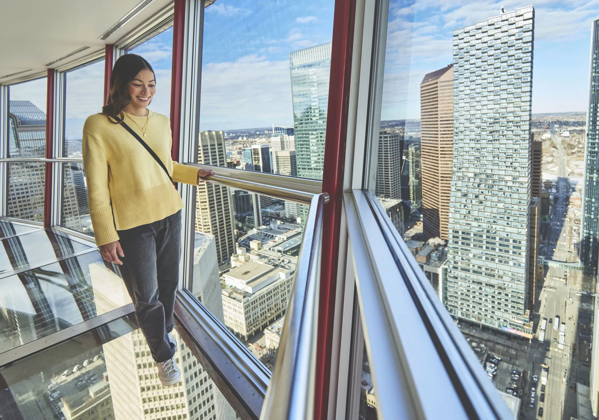 Woman standing on the Calgary Tower glass floor looking out to the horizon
