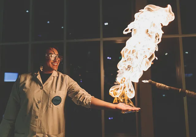 demonstrator at TELUS Spark science centre holding flame in her open palm