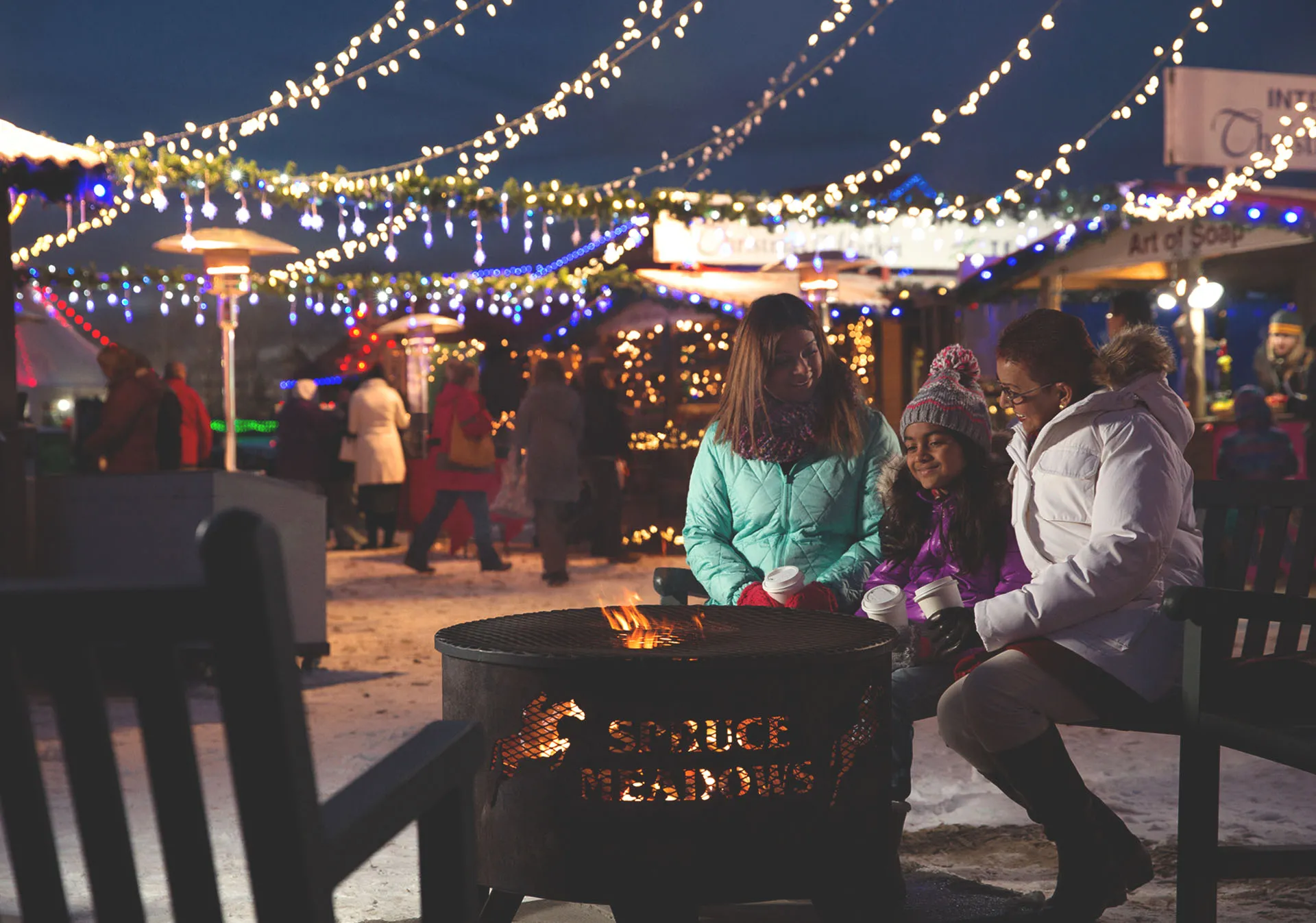 family sitting around a fire at Spruce Meadows International Christmas Market