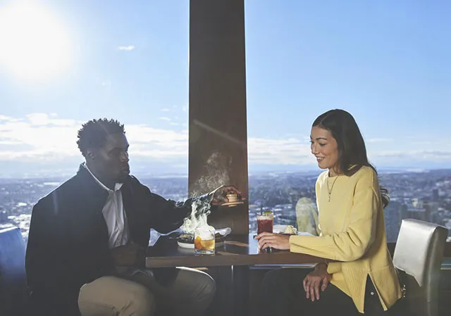 couple dining at Sky360 and enjoying the presentation of a smoking cocktail at their table