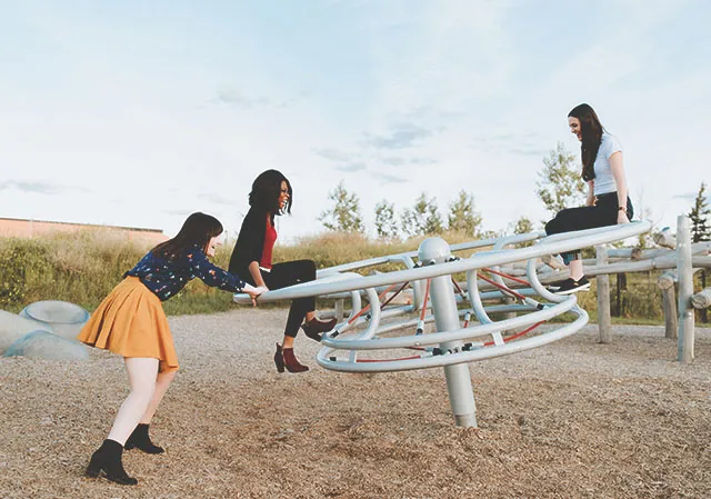 three friends playing on structures outdoors at TELUS Spark