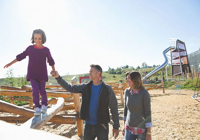 family of three playing on TELUS Sparks outdoor park