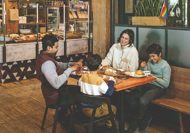 Family sits at a table inside Sidewalk Citizen enjoying baked treats