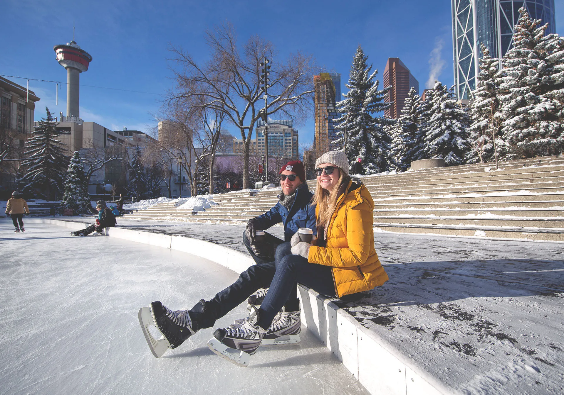 couple sit off ice to enjoy a warm drink at Olympic Plaza in downtown Calgary