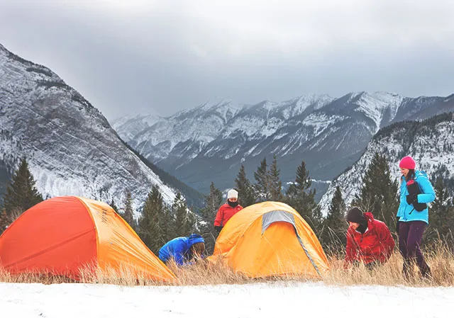 A group of people setting up tents for winter camping at Tunnel Mountain Campground in Banff National Park