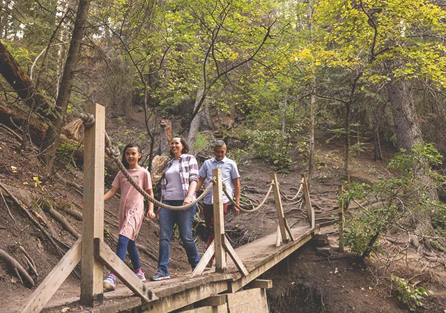 family hiking along a wooden bridge in the woods of the Douglas Fir trail
