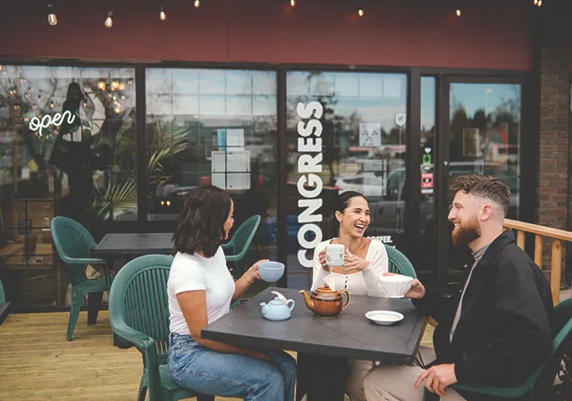 friends sitting at an outdoor patio table enjoying tea from Congress Coffee