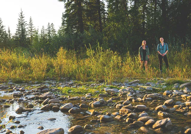 two ladies pausing in front of a small creek during a hike in Fish Creek Park