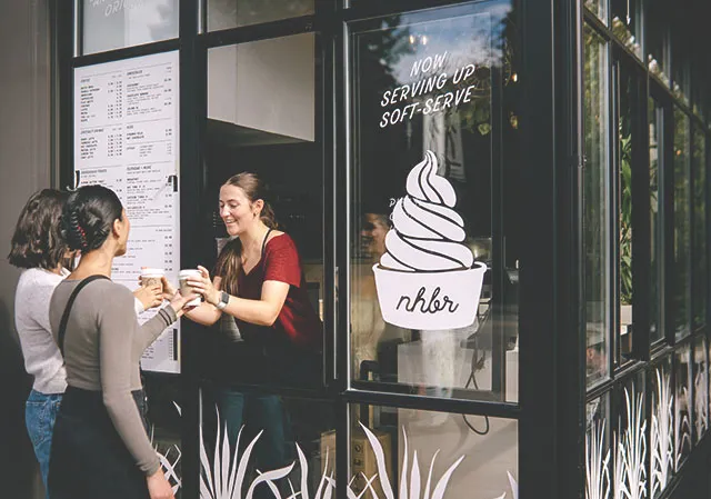 barista serves two ladies coffee from a takeout window at NHBR coffee