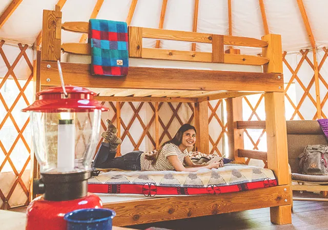 woman on a bunkbed inside a glamping yurt