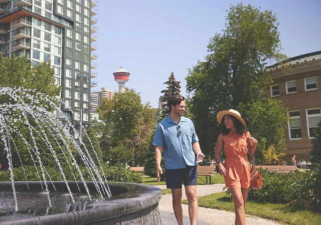 couple walks next to a water fountain in Central Memorial Park in downtown Calgary