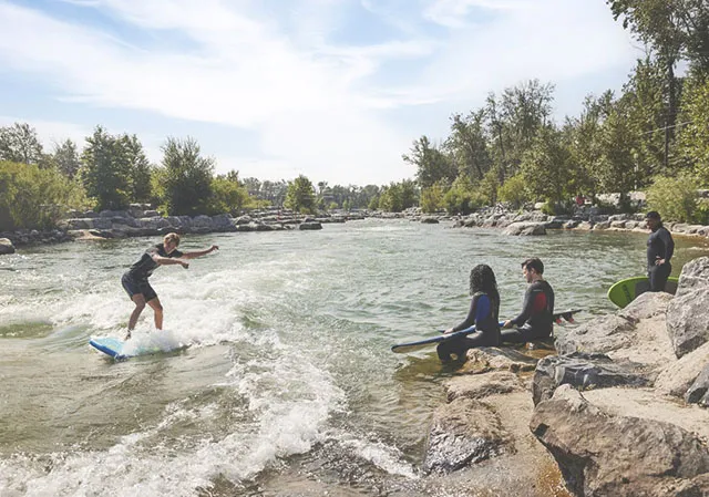 group of friends try river surfing at Harvie Passage