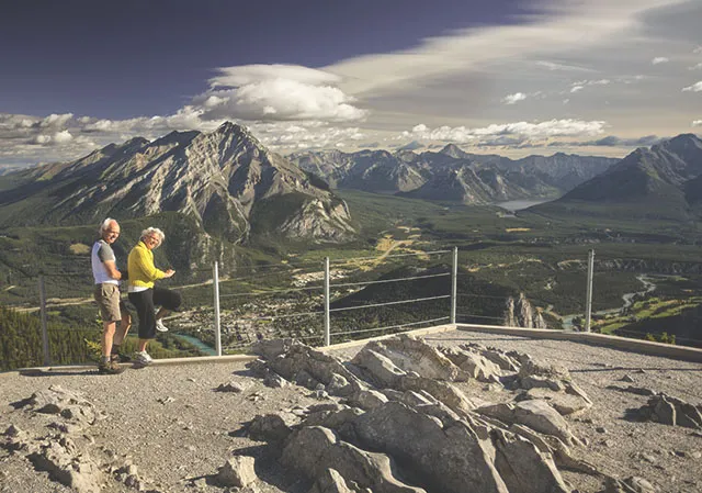 a older couple enjoys sweeping views of Banff National Park from the Sulphur Mountain Comic Ray Station Viewpoint