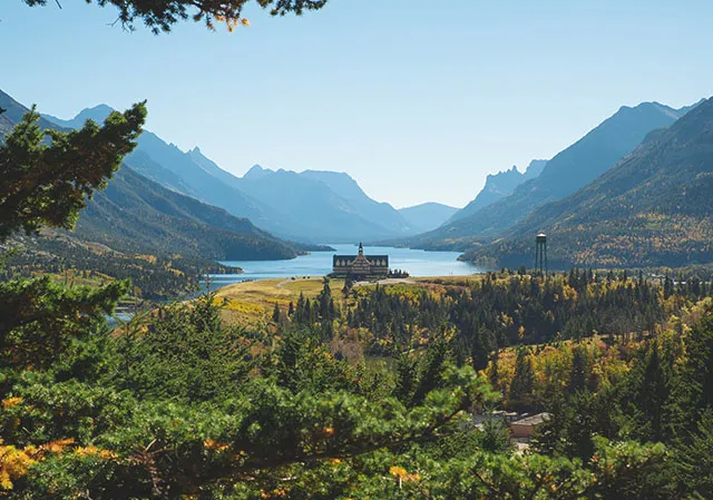 Scenic view of the Prince of Wales Hotel surrounded by forest and mountains in Waterton Lakes National Park