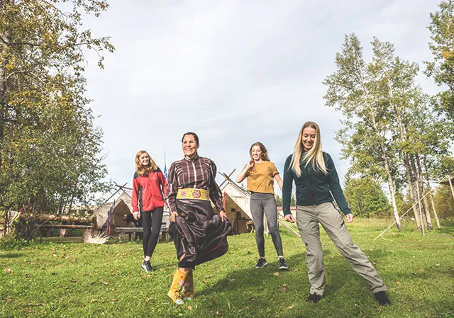 group of ladies are lead by an indigenous woman through traditional dancing at Rocky Mountain National Historic Site