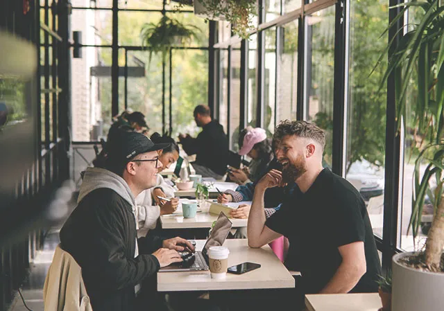 friends sitting inside the solarium dining area at Neighbour Coffee in Altadore