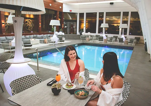 Two women eating lunch by the all season pool at Hotel Arts in Calgary