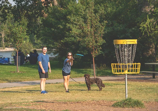 couple and their dog playing disc golf in Baker park