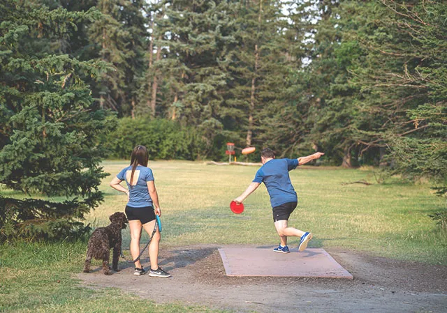 couple and their dog playing disc golf in Baker park