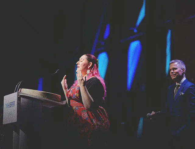a woman speaking at a podium on stage at Calgary TELUS Convention Centre