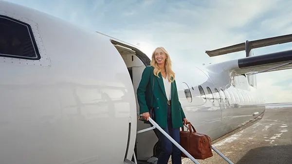 a woman is stepping off a plane with a bright smile
