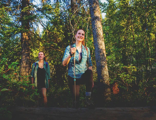 two women walking through the woods on a trail in Fish Creek Park